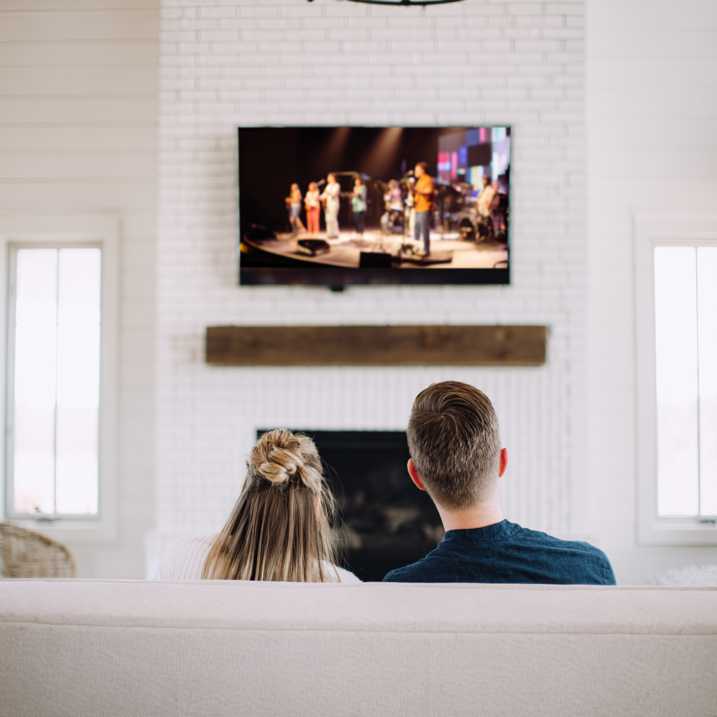 Young married couple watches a live streamed church service on TV on Sunday morning.
