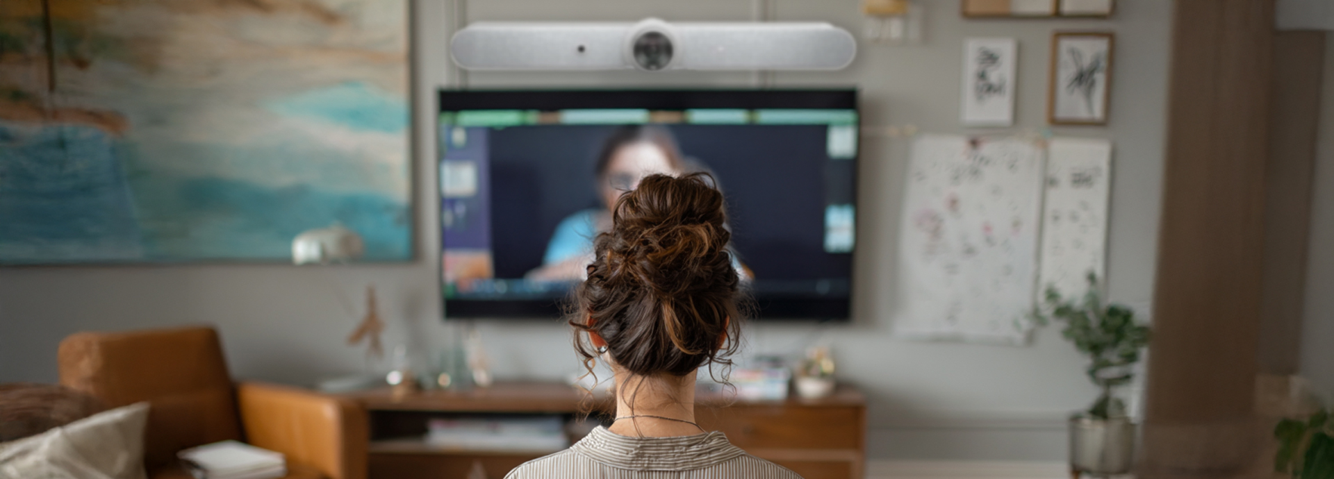A therapist using a dedicating room with a teleconference bar to communicate with a client for a therapy session via web conference.